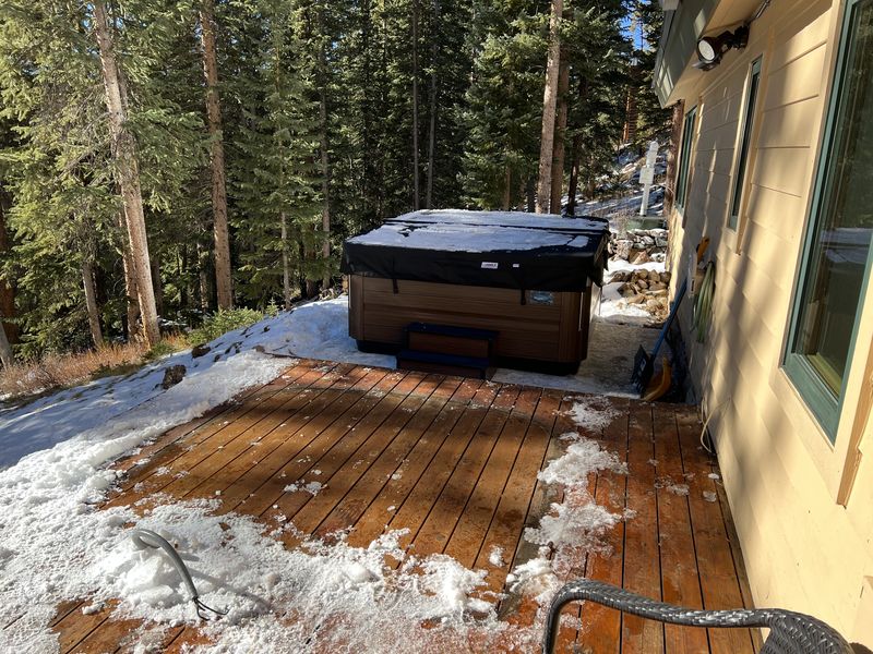 Hot tub on the winter deck with snow and pines