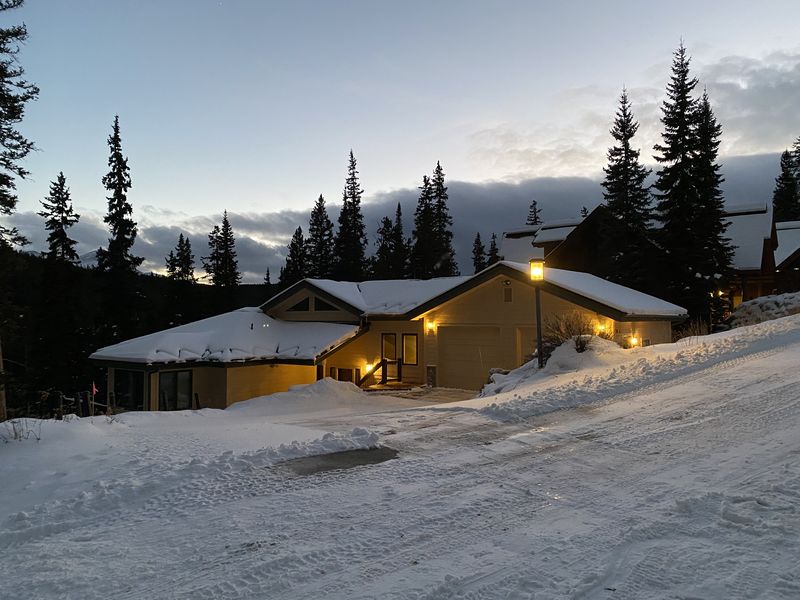 The house at dusk with warm lights glowing against the snow